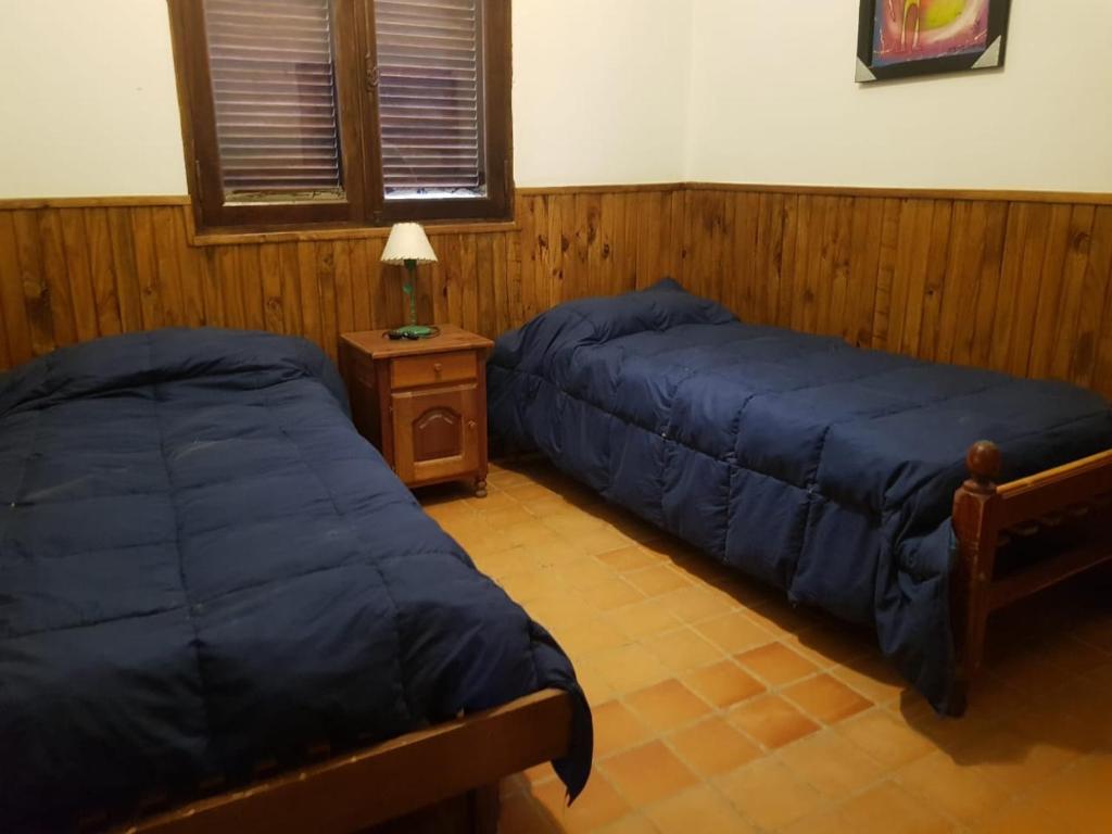 a bedroom with two beds and a night stand with a lamp at SumayWasi in Tilcara