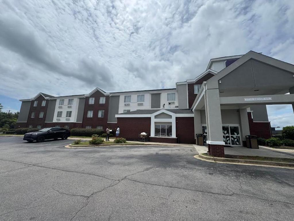 a building with a car parked in a parking lot at Broad St Inn in Sumter