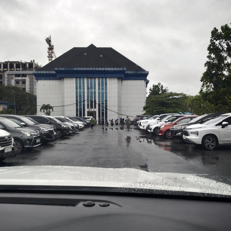 a parking lot with cars parked in front of a building at Hotel in Puunggolaka