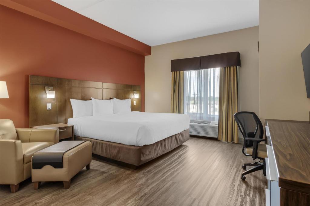 a hotel room with a bed and a desk and chairs at Best Western Plus Winnipeg West in Winnipeg
