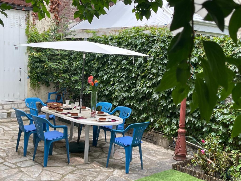 a table with blue chairs and a white umbrella at Lovely house with garden Paris Flea Market in Saint-Ouen
