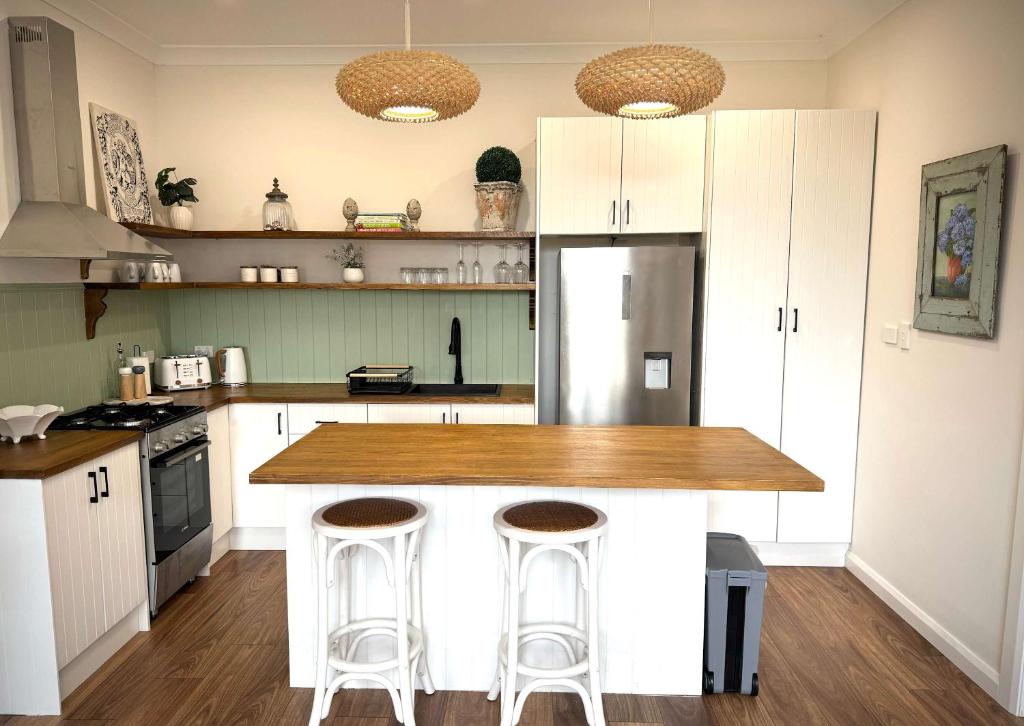 a kitchen with white cabinets and a counter with stools at The Summer Cottage in Orange