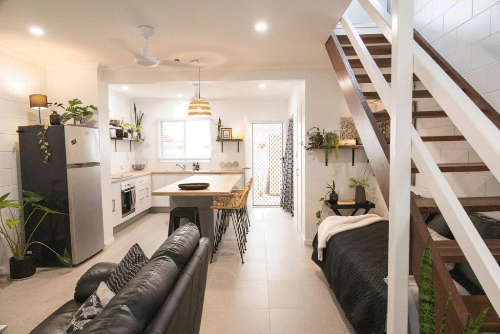 a kitchen and a living room with a staircase at Whitsunday Pandanus-Stylish 2 bedroom townhouse in quiet location in Cannonvale