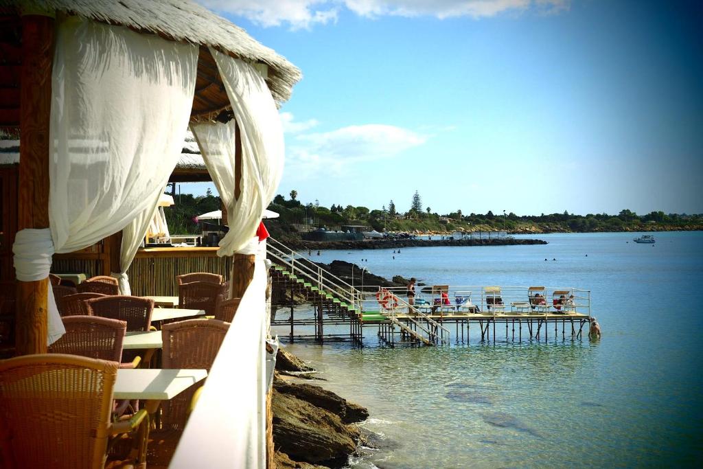 a restaurant with a dock in the water with tables and chairs at Residence Arenella in Arenella