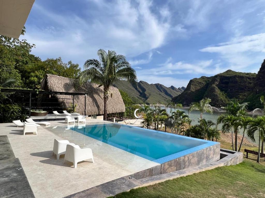 a swimming pool with white chairs and a resort at Mansion del Lago - Hotel Prado in Prado