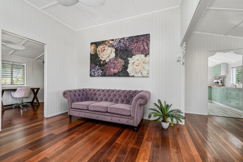 a couch in a living room with a painting on the wall at Charming Queenslander Retreat in Mundingburra in Rosslea