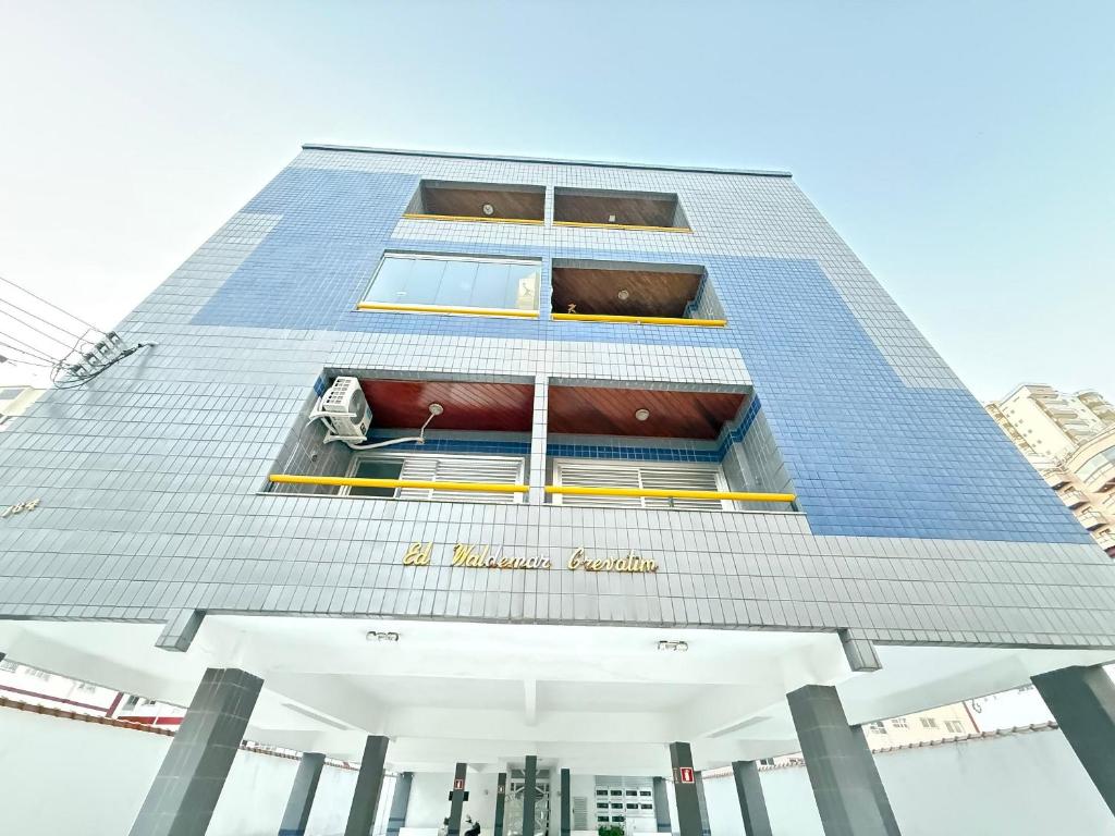 a tall blue building with a sign on it at Pé na Areia Praia da Tupi II in Samaritá