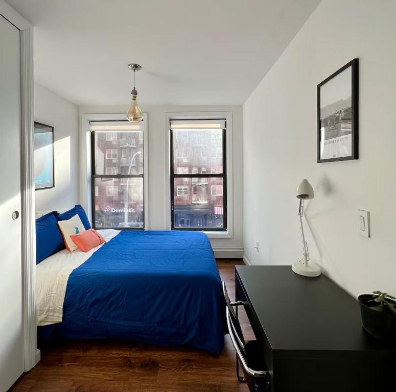 Un dormitorio con una cama azul y dos ventanas. en Chelsea Gem Modern 2BR Apt Prime 23rd & 7th Spot, en Nueva York