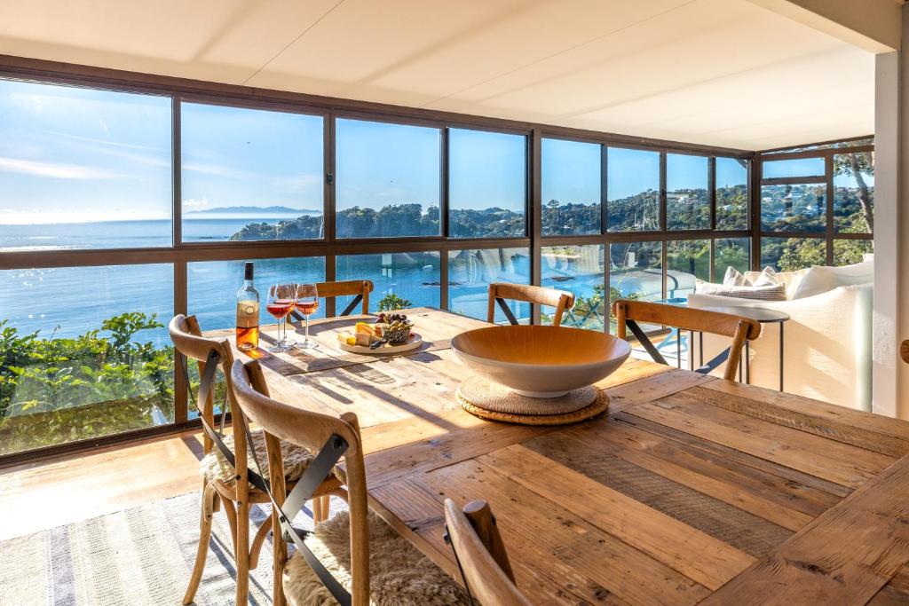 comedor con mesa y vistas al océano en Clifftop Sanctuary - Stay Waiheke, en Oneroa