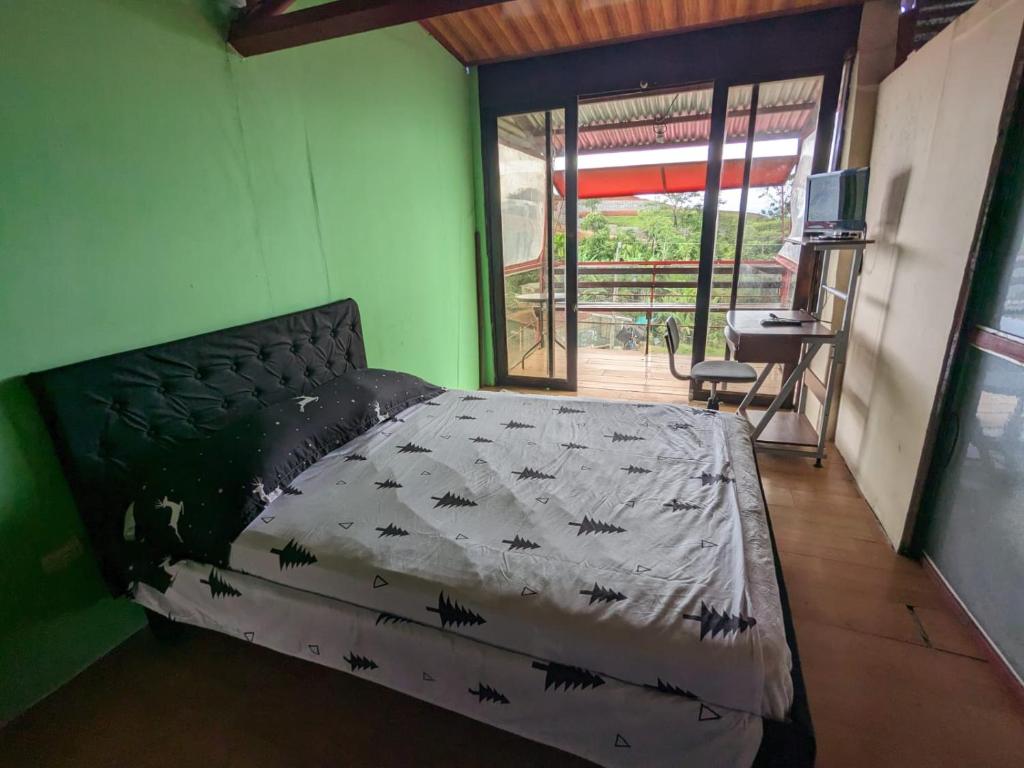 ein Schlafzimmer mit einem Bett in einem Zimmer mit einem Schreibtisch in der Unterkunft Alojamiento el Mirador in Tapantí