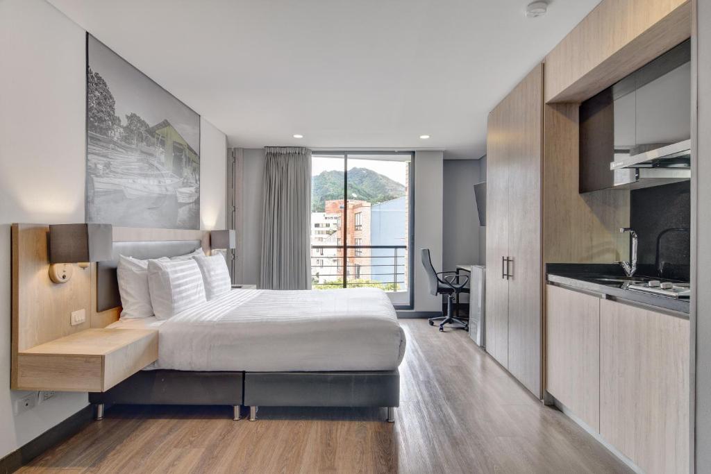 a hotel room with a bed and a kitchen at Loft Home Suites 118 By gA in Bogotá