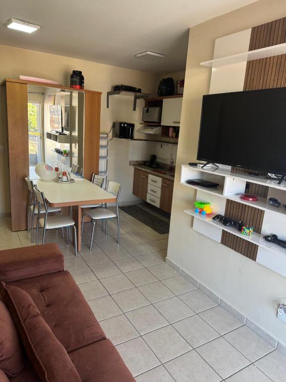 a living room with a table and a television on a wall at Serra Park in Rio Quente
