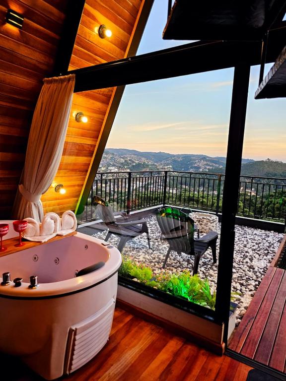 a bathroom with a tub and a balcony with a view at Chalé Super Luxo Monte Lorobell in Campos do Jordão