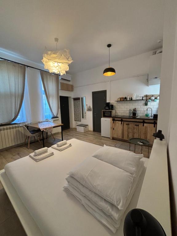 a large white bed in a room with a kitchen at Next Door Studio in Cluj-Napoca