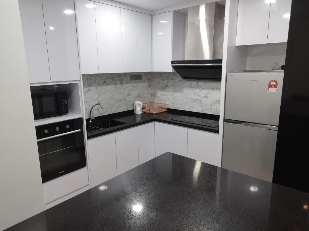 een keuken met witte kasten en een zwart aanrechtblad bij My Residence Villa Times Square KL in Kuala Lumpur