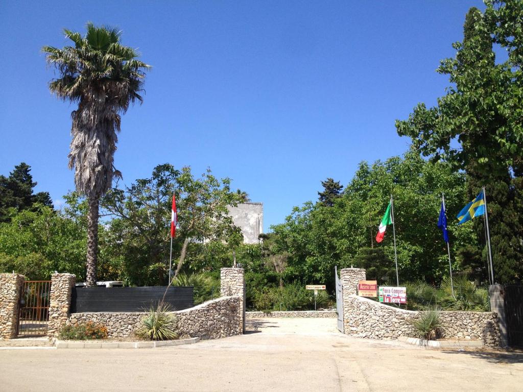 a park with flags in front of a palm tree at Masseria Lama in Torre dell'Orso