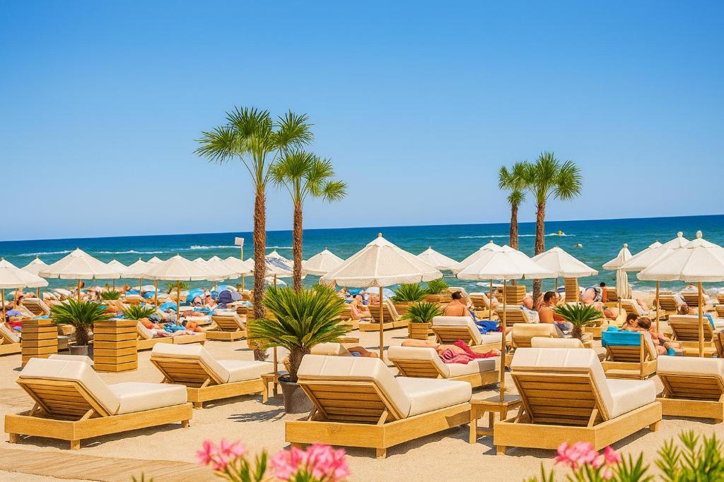 a beach with lounge chairs and palm trees and the ocean at Lilly Studio Axxis Beach in Mamaia