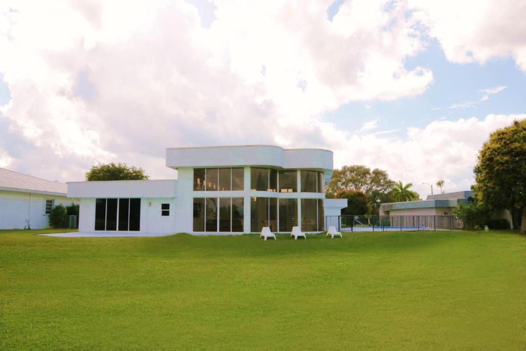 a white building with two white chairs in a field at The Monochrome Villa in Fort Lauderdale