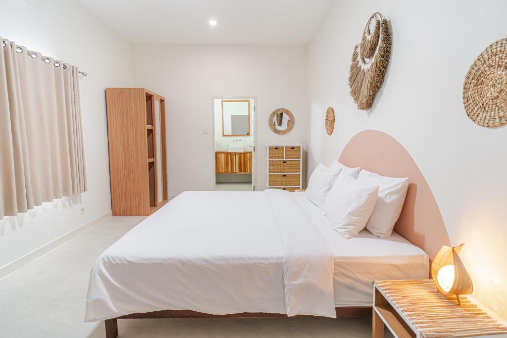 Un dormitorio blanco con una cama y una mesa. en Semeton Villas, en Gili Trawangan