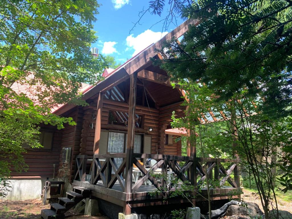 eine Blockhütte im Wald mit Bäumen in der Unterkunft ルネス軽井沢-高原の貸切コテージでBBQ and 焚火を満喫- in Tsumagoi