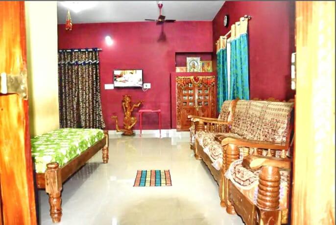 a living room with two couches and a red wall at Nelligudda Homestay in Kalasa