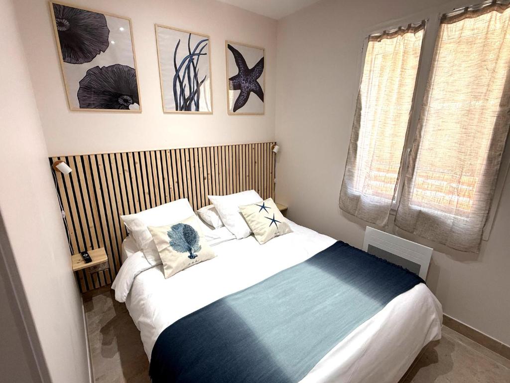 una camera da letto con un letto con lenzuola e cuscini bianchi di La Villa Mar Y Sol - Bord de mer a Fos-sur-Mer