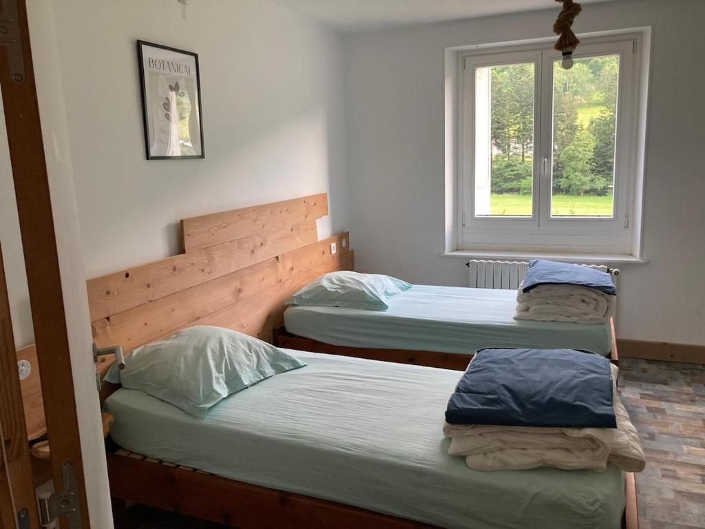 three beds in a room with a window at Le Gîte d'Orion in La Bresse
