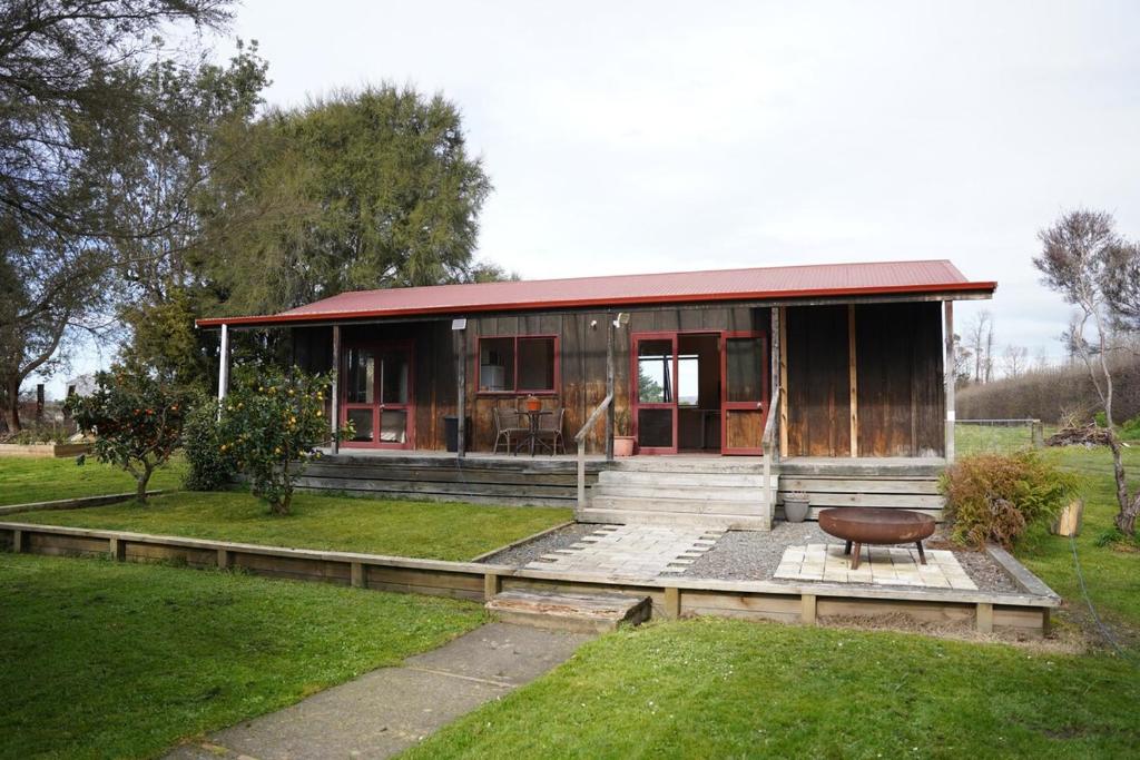 a home with a red roof and a bench in the yard at Country Cutie-Pie, close to town in Hastings