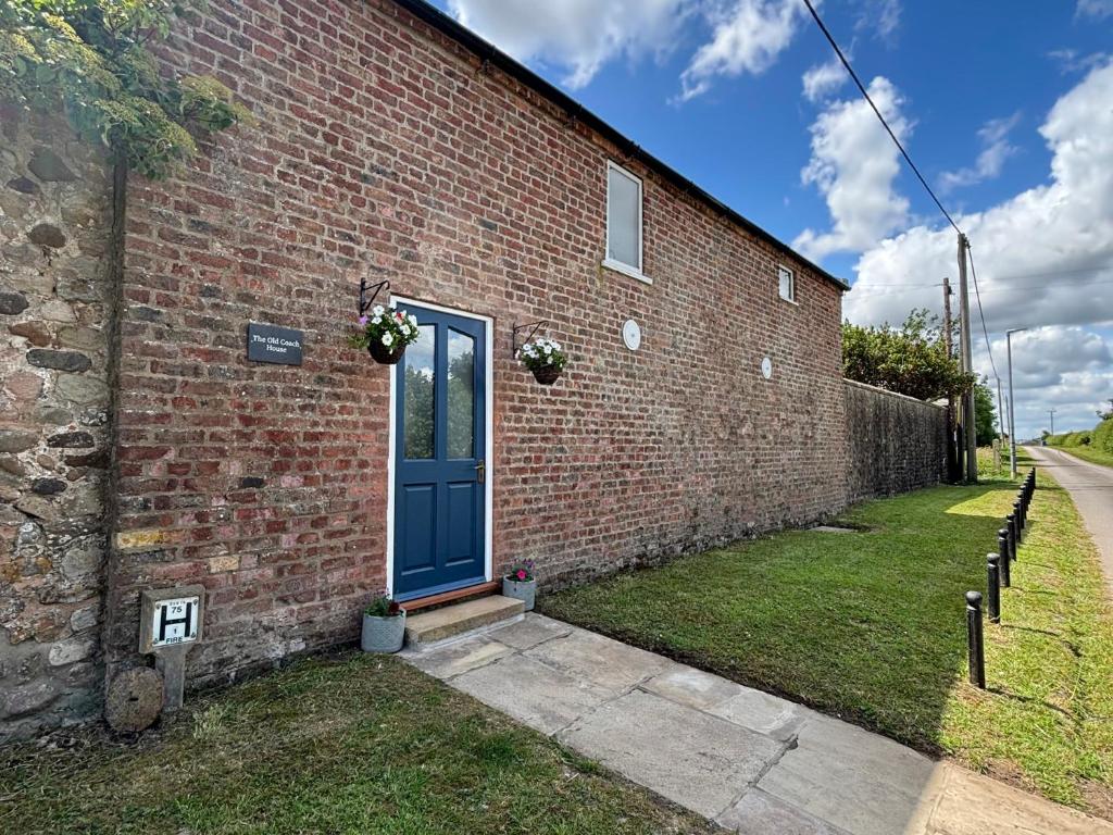 Un edificio de ladrillo con una puerta azul. en The Old Coach House at The Vicarage, en Hornsea