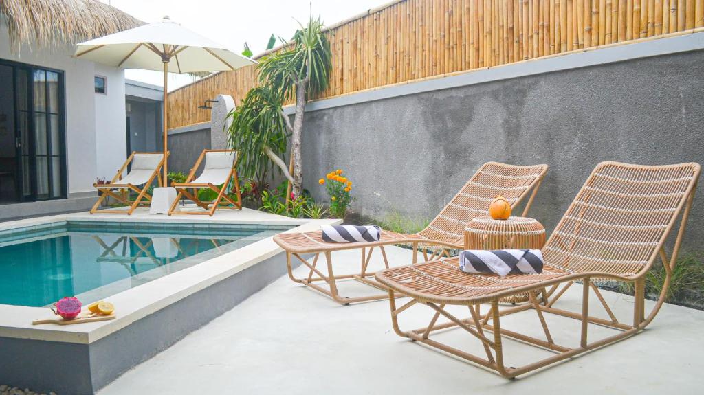 two chairs and a table next to a swimming pool at Pandan Villas, Canggu in Dalung