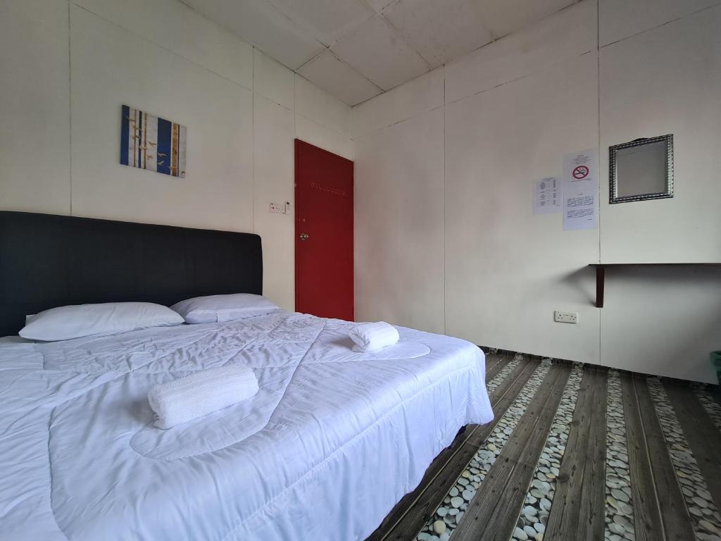 a bedroom with a bed with white sheets and a red door at MAZ Borneo Ventures 2 in Labuan