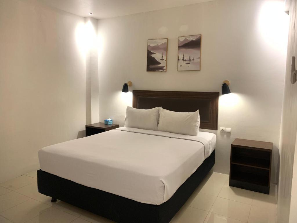a bedroom with a large bed with white sheets at Hotel Harmony in Batulicin
