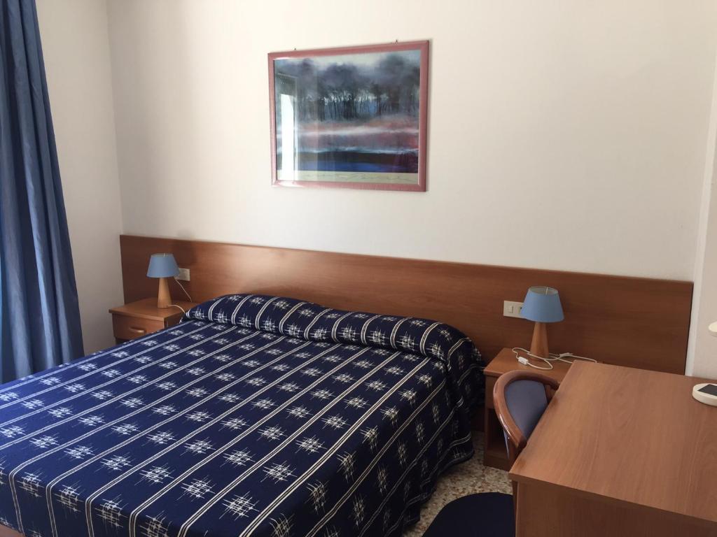 una habitación de hotel con una cama y una foto en la pared en Pensione Giardino, en Lignano Sabbiadoro