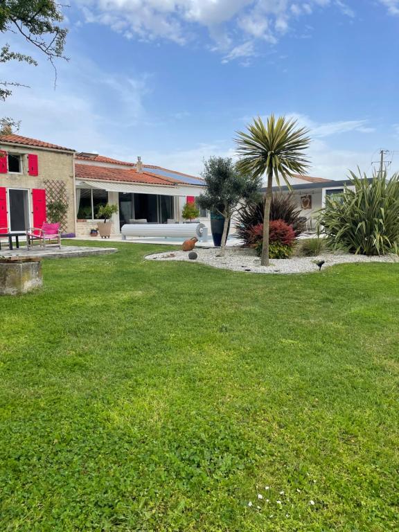 une maison avec une cour dotée d'une pelouse verdoyante dans l'établissement Charentaise contemporaine, à Anais