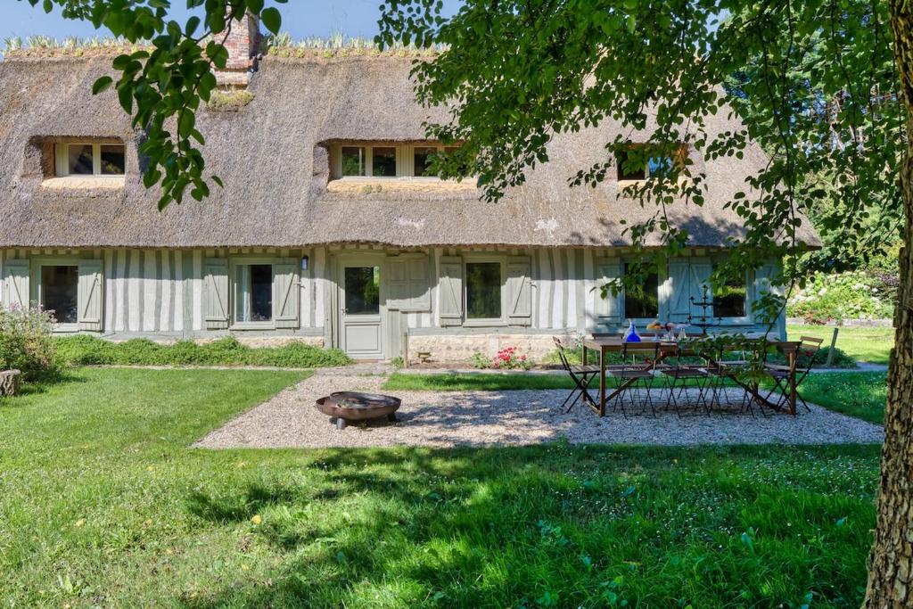 a house with a picnic table in the yard at La maison du fermier in Saint-Wandrille-Rançon