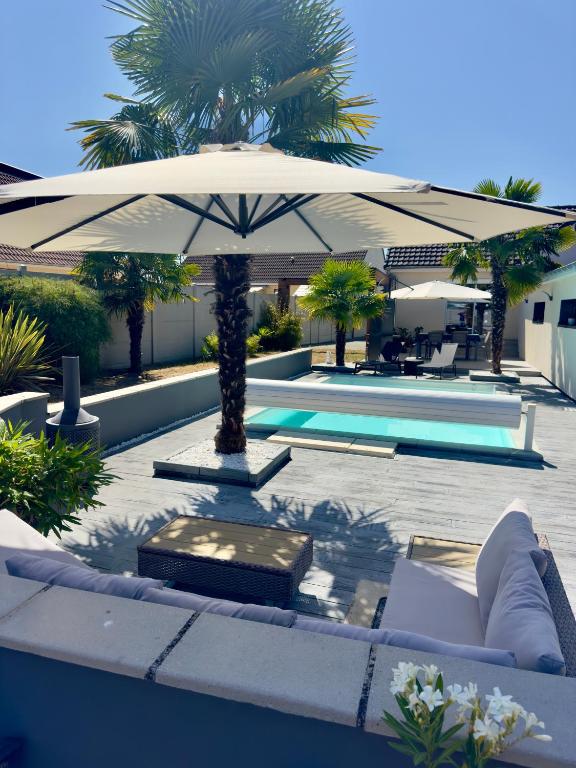 - une terrasse avec un parasol à côté de la piscine dans l'établissement Chambre chez l'habitant avec piscine 400m Circuit 24h Le Mans, au Mans