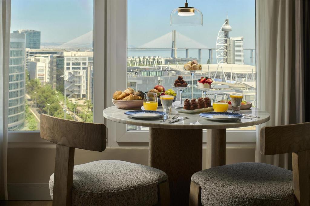 A breakfast table set beside a panoramic city and waterfront window.