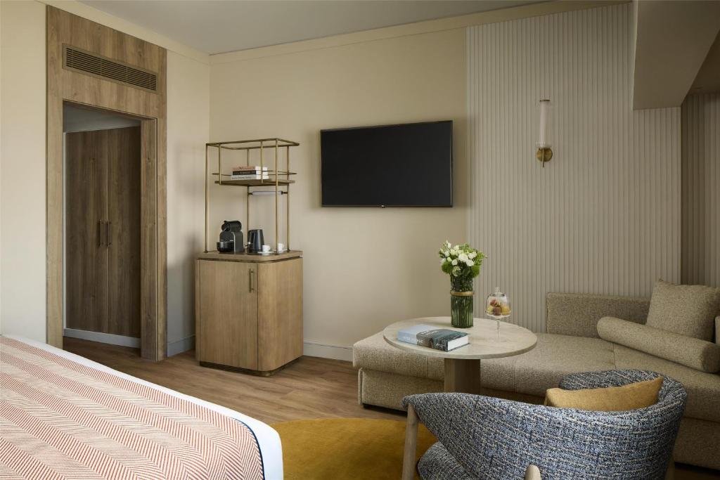 A bedroom sitting area with a wall-mounted television and beverage cabinet.