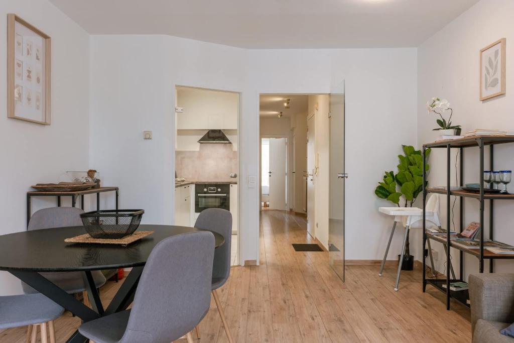 a dining room and living room with a table and chairs at Huswell - Bright & Stylish Apartment with Balcony in Knokke-Heist