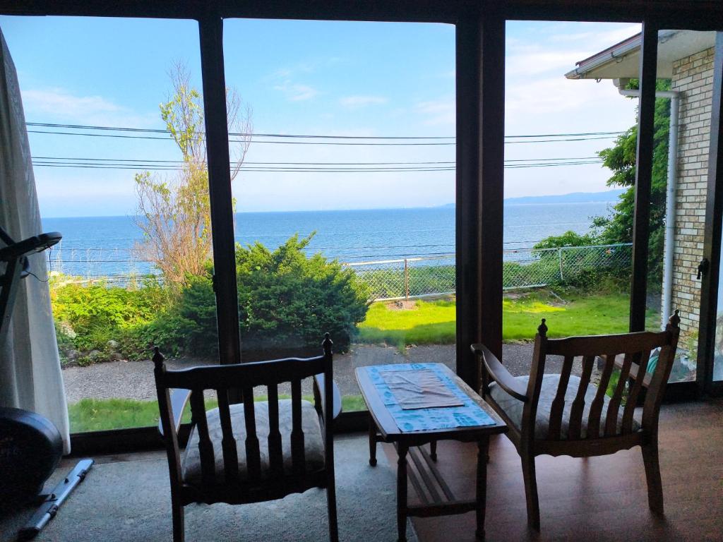 un patio con tavolo, sedie e vista sull'oceano di 旅館青柳 海越し立山連峰の雪山絶景で休もう a Himi