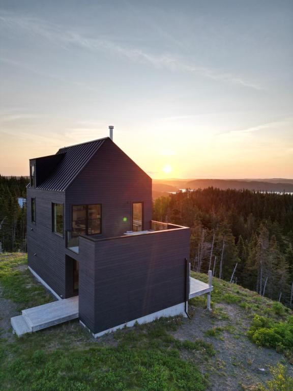 a house on a hill with the sunset in the background at City View Charm St John's 1br, 8min To Downtown in Port Rexton
