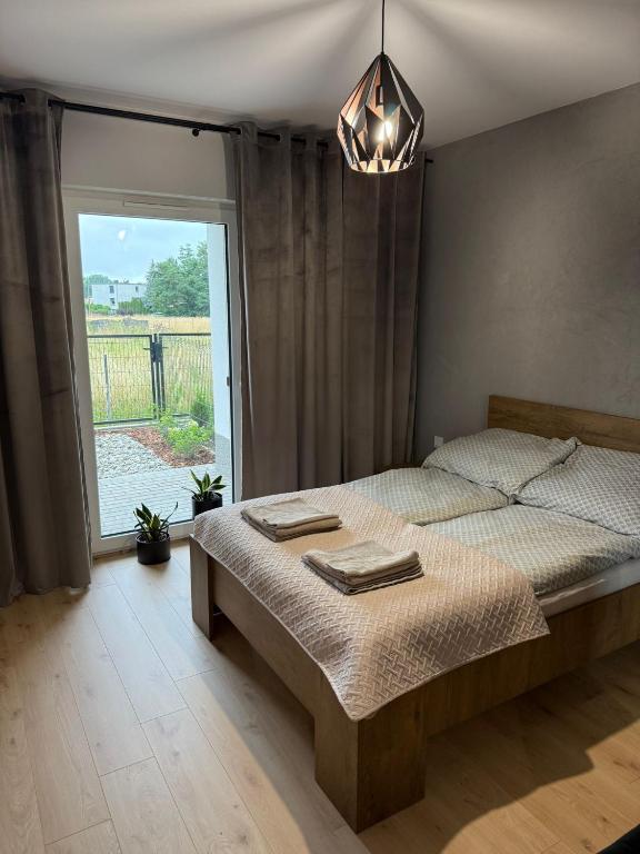 a bedroom with a bed and a large window at Słoneczny Apartament Karpicko in Karpicko