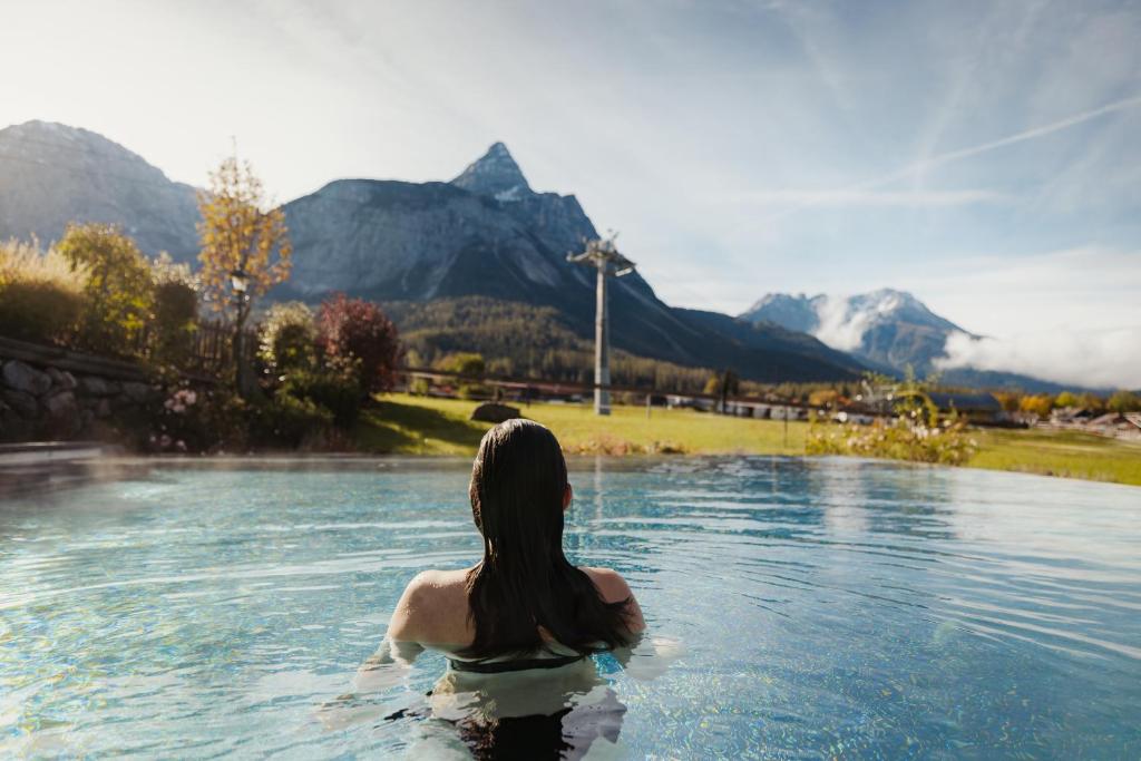 a woman in a pool of water with mountains in the background at Hotel Spielmann 4s in Ehrwald