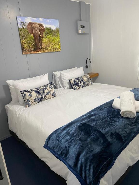 a bed with a blue blanket on top of it at Sundays River Tiny homes - 5 min from Addo Park South Gate in Gqeberha
