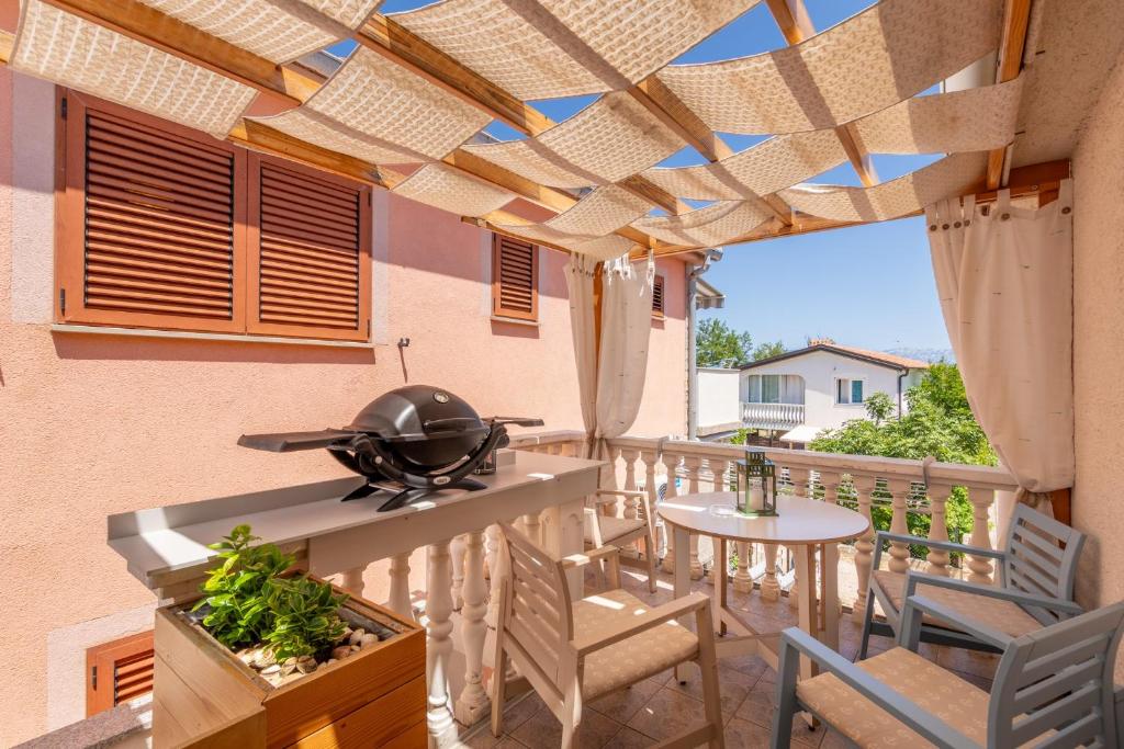 een patio met een grill en een tafel en stoelen bij Apartment Siranovic in Batalaži