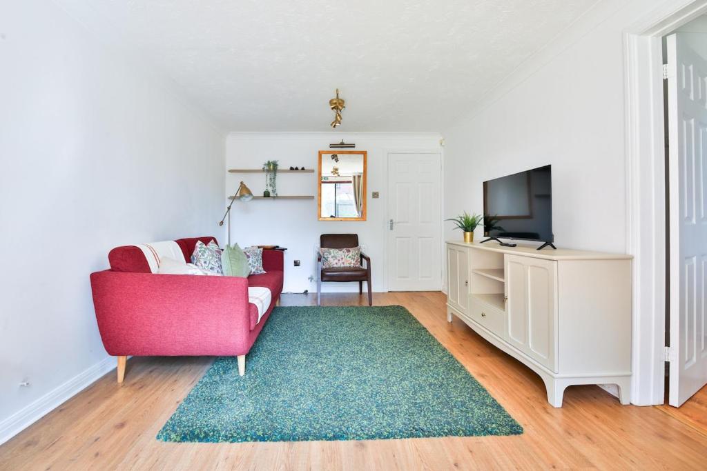 un salon avec une chaise rouge et une télé dans l'établissement Homely 5 Bed House - 15 Mins to Cardiff City, à Cardiff