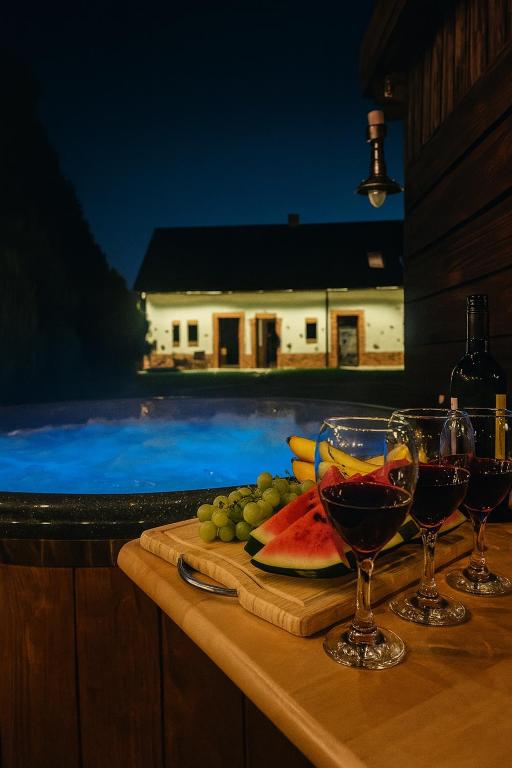 two glasses of wine and fruit on a table next to a swimming pool at Miejski Las 8 in Mrągowo