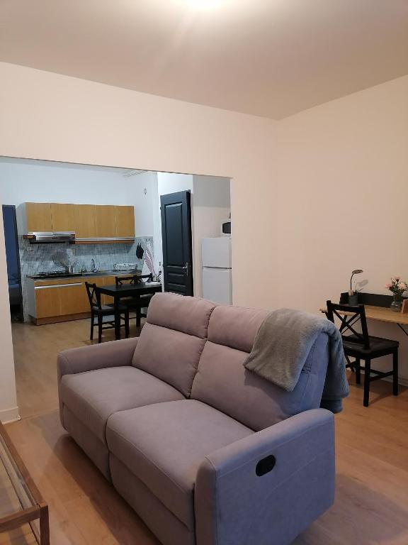a living room with a couch and a kitchen at Appartement en centre ville in Ambert