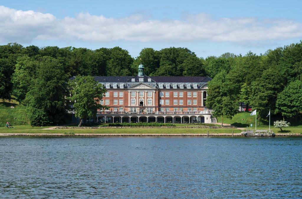 um grande edifício vermelho ao lado de uma massa de água em Hotel Koldingfjord em Kolding