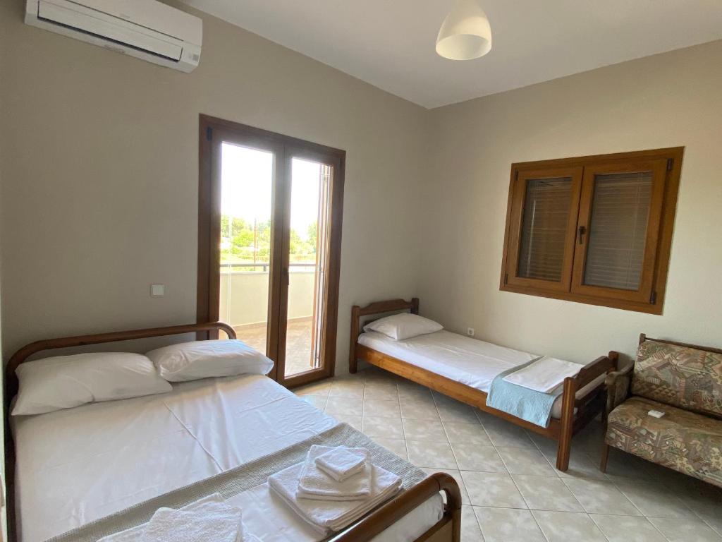 a bedroom with two beds and a couch and a window at Aphrodites Gardens in Ormos Panagias